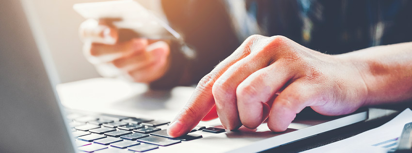 Person sitting at a keyboard with a credit card