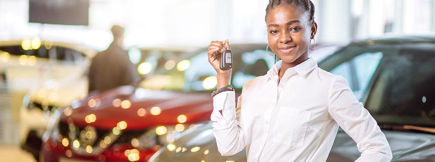 Woman holding car keys in front of a car