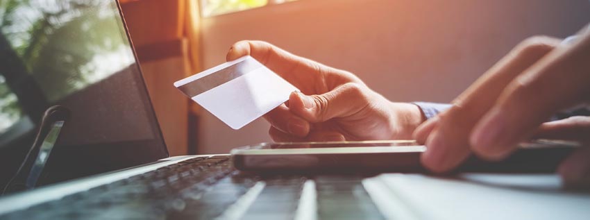 Person holding a credit card in front of a laptop