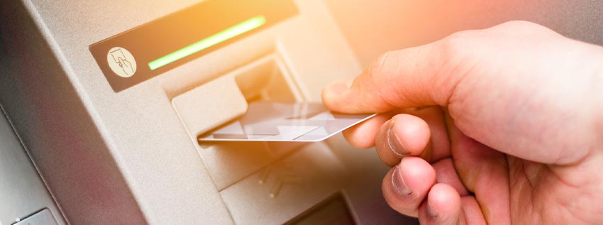 Person inserting a debit card into an ATM