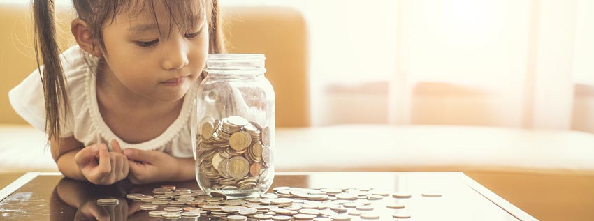 Young girl looking at a savings jar with coins