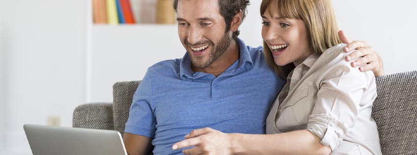 Couple sitting on couch with their laptop