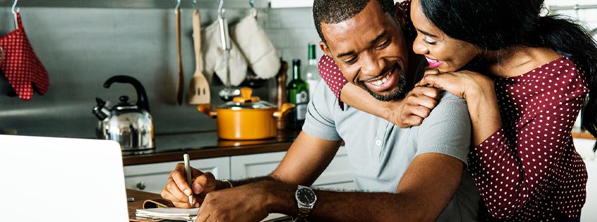 Couple hugging and looking at laptop