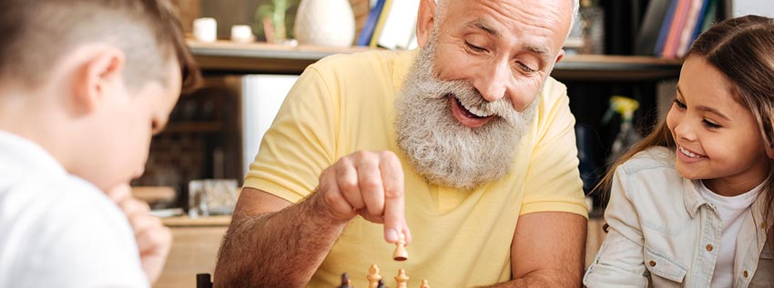 Older man playing chess with kids