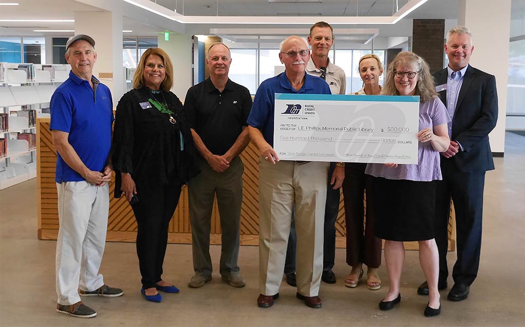 RCU team holding a large check in the library