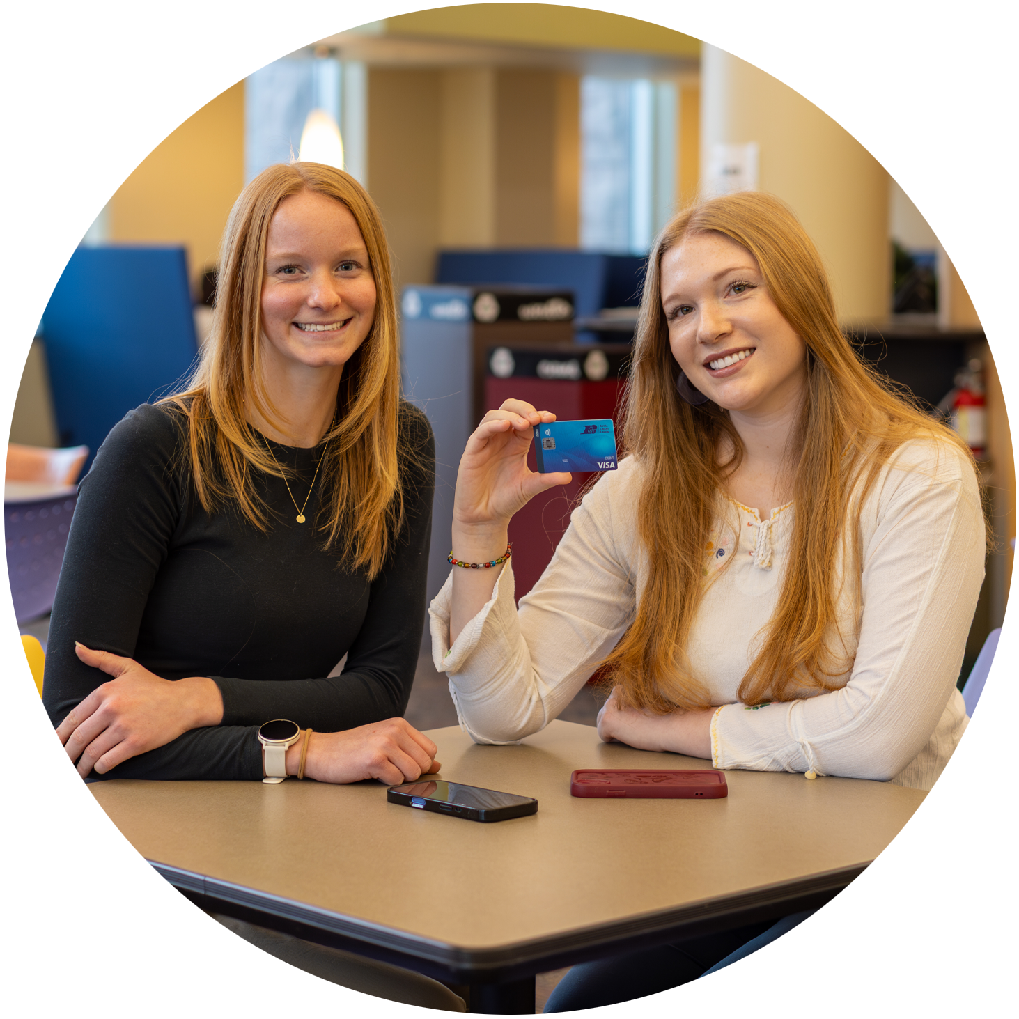 two young women sititng togather holding a debit card