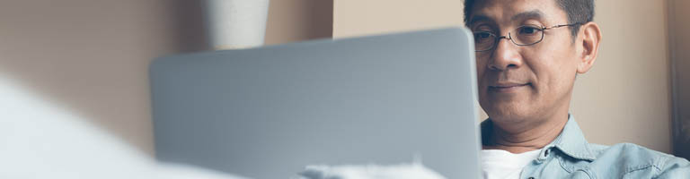 man with glasses looking at a laptop screen