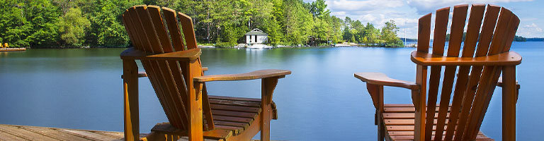 Two empty chairs in front of a lake