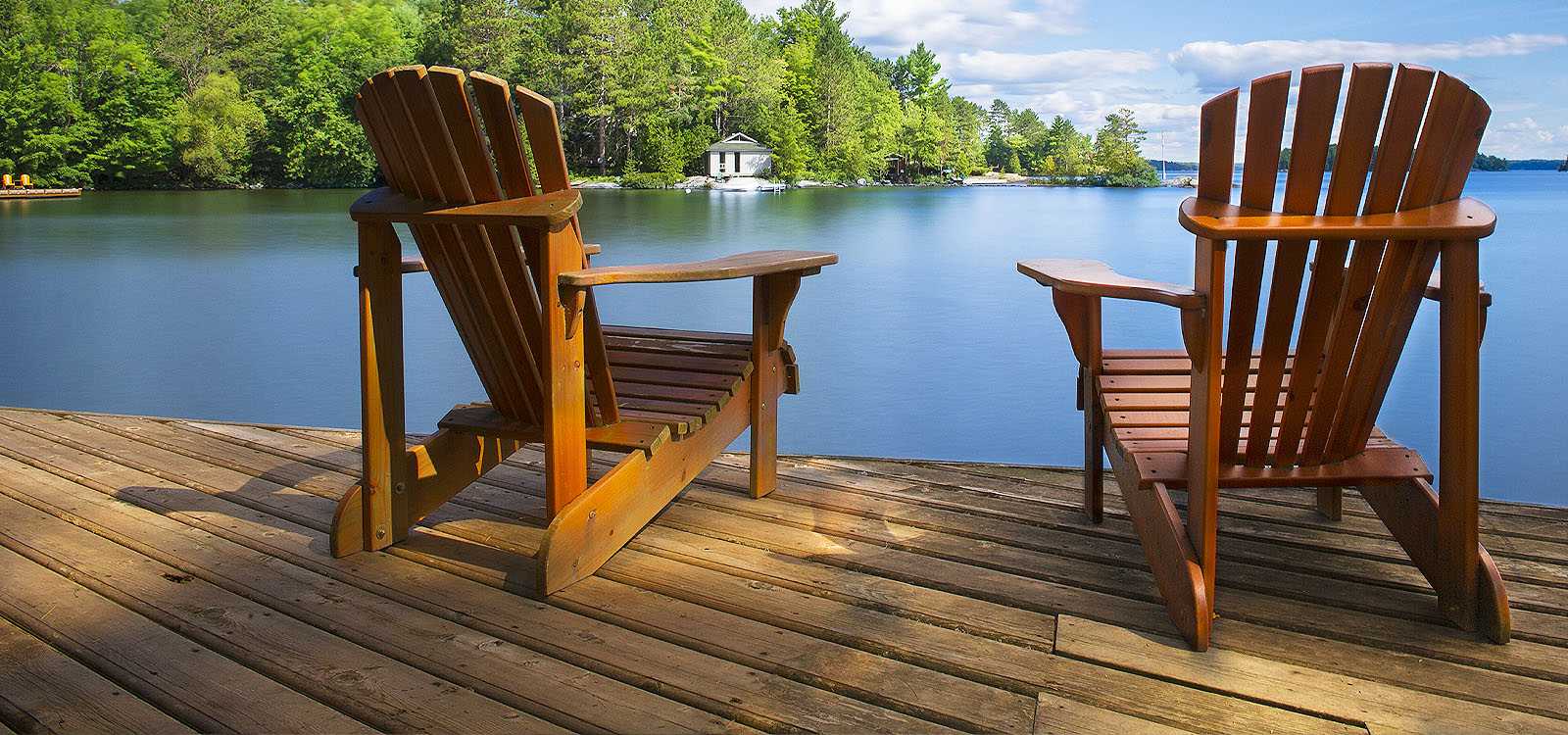 Two empty chairs in front of a lake