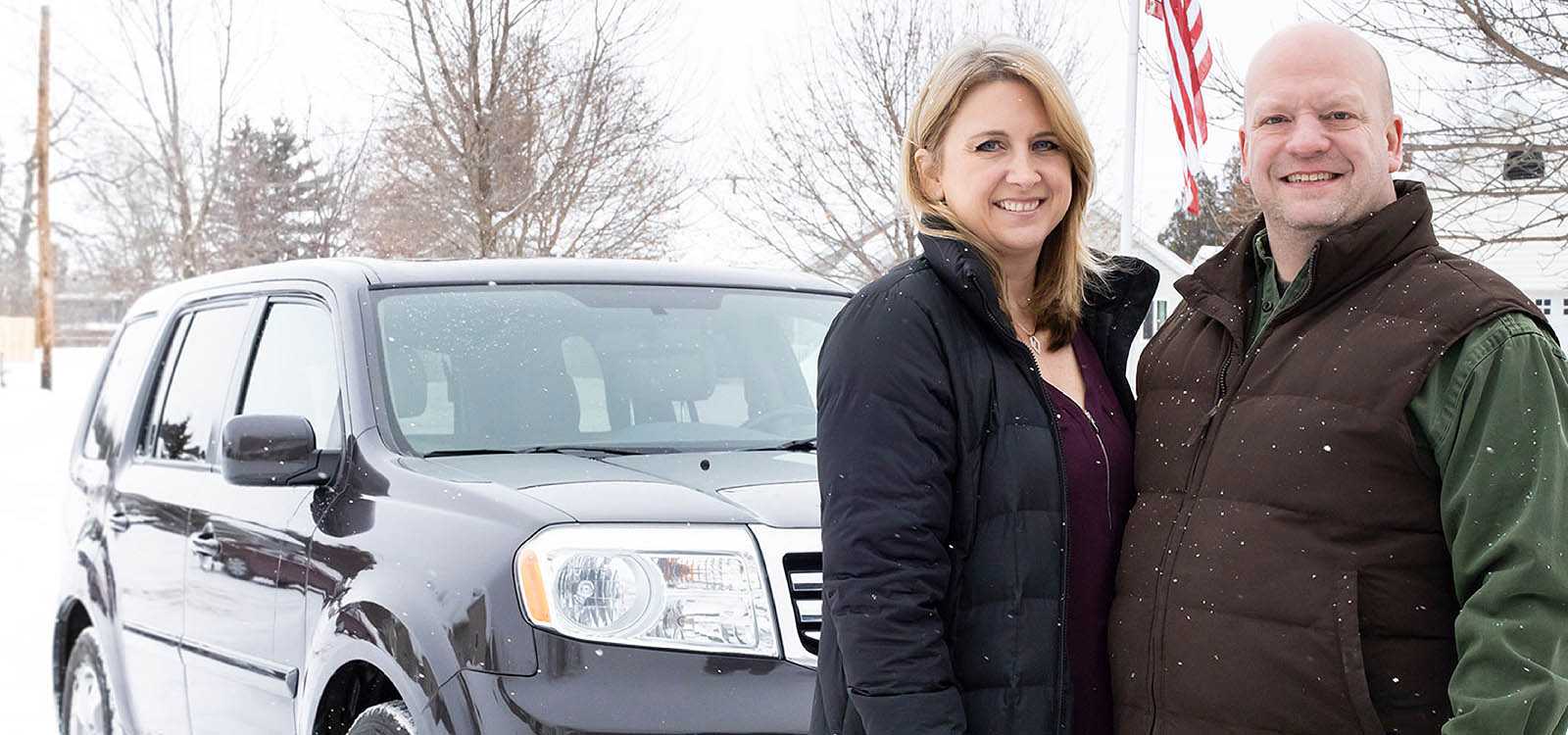 Couple standing in front of new car