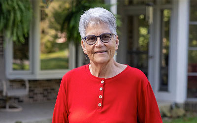 Older woman standing in front of her house