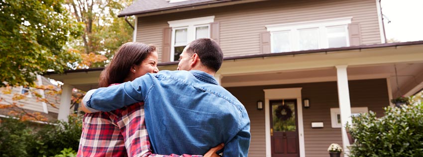 Couple standing in front of their house
