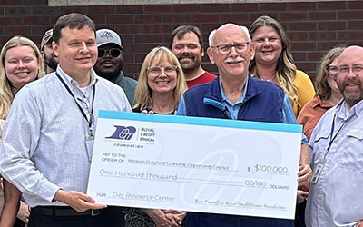 Group of RCU leaders and WDEOC leaders holding a check in front of the building
