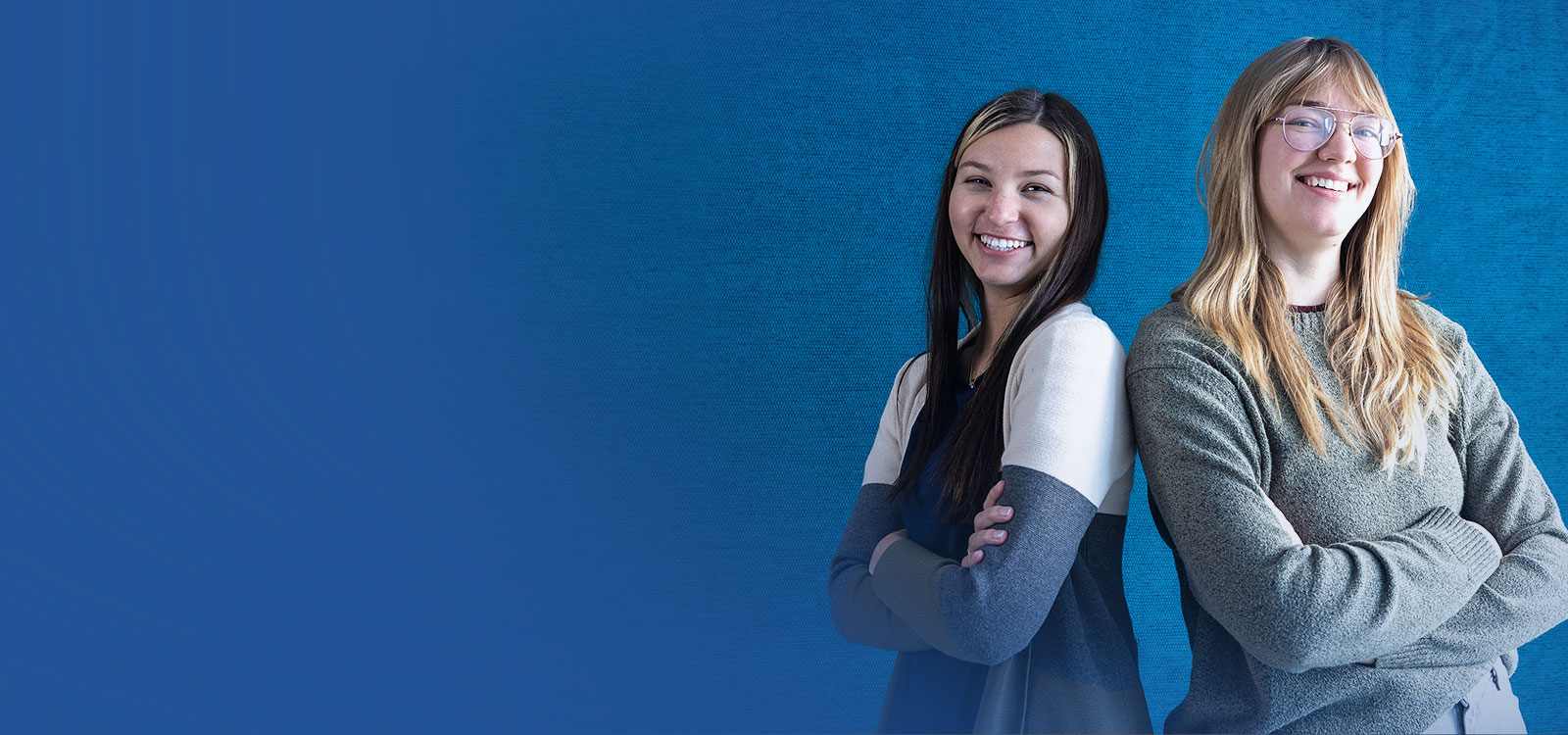Young women standing back to back smiling