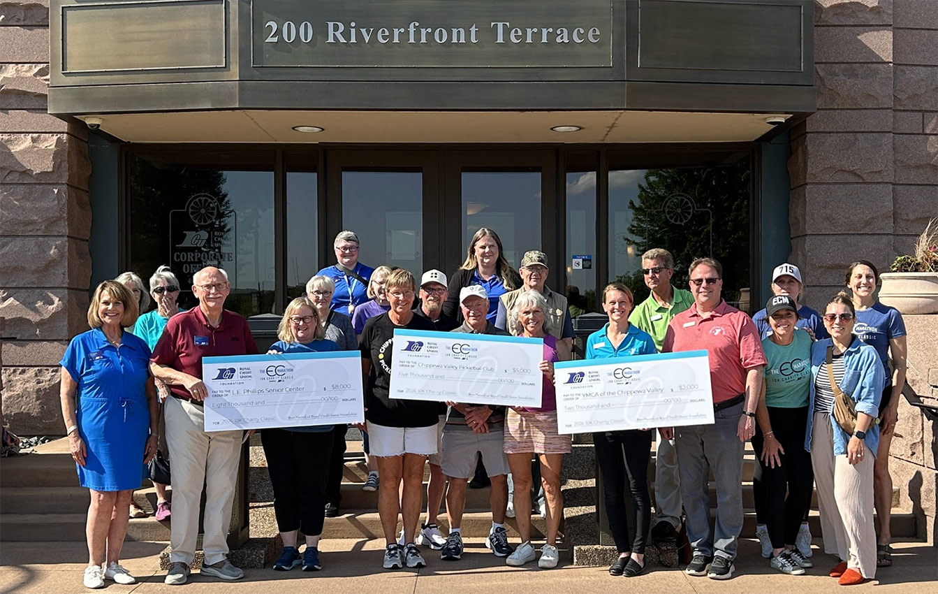 Photo of RCU leadership and recipients receiving large checks in front of RCU corporate center