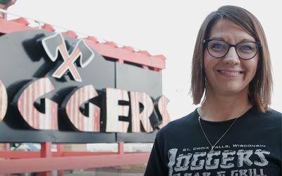 Business Member standing in front of Loggers sign