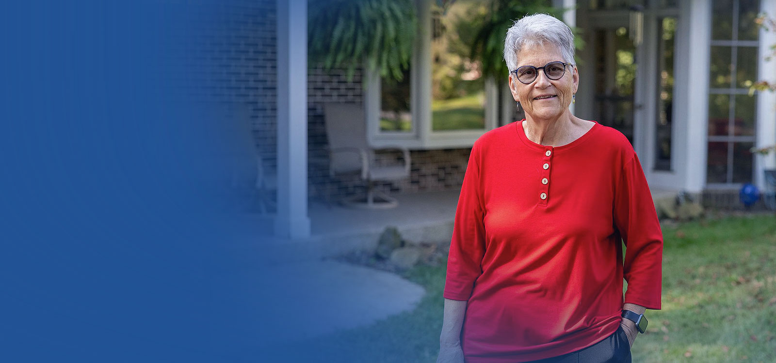 Older woman standing in front of her house