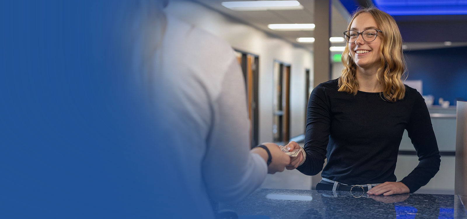 Young adult woman in at an RCU Office with a teller