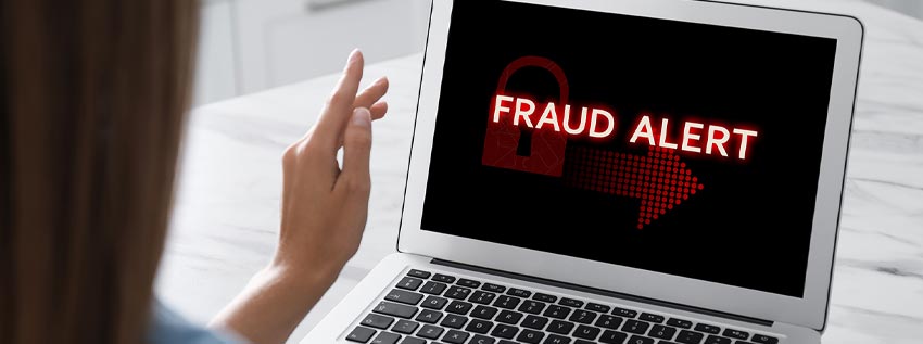 Person on a laptop with with the word Fraud on the screen