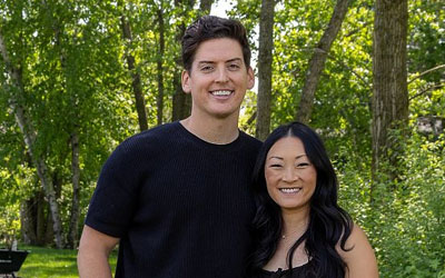 Pregnant couple standing near their home