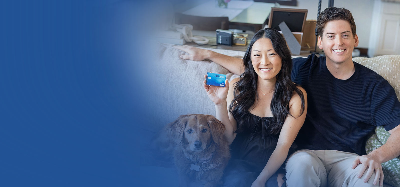 Woman holding an RCU debit card with her husband and dog