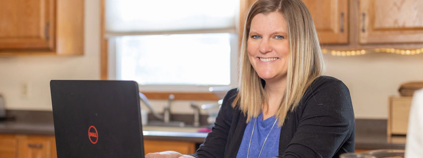 Woman looking at the camera on her laptop managing her loan