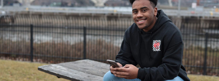 Young man sitting on a bench in the park on his phone