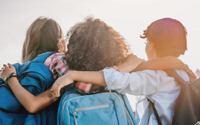 Kids hugging with backpacks