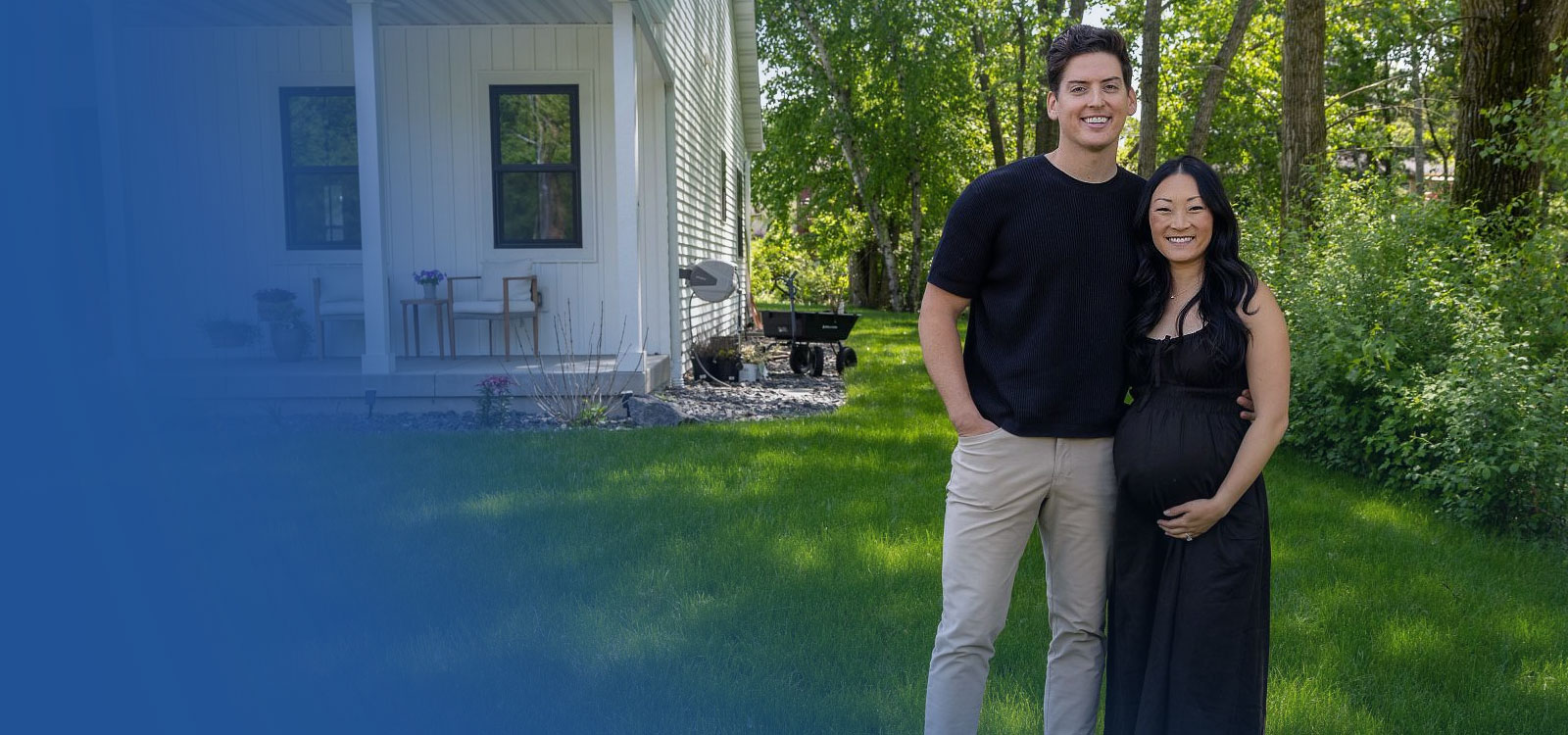 Pregnant couple standing near their home