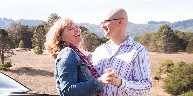 Happy middle aged couple in front of car