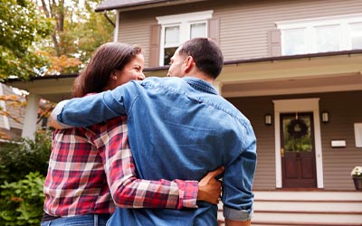 Couple standing in front of their house