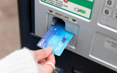 Person inserting an RCU debit card into ATM