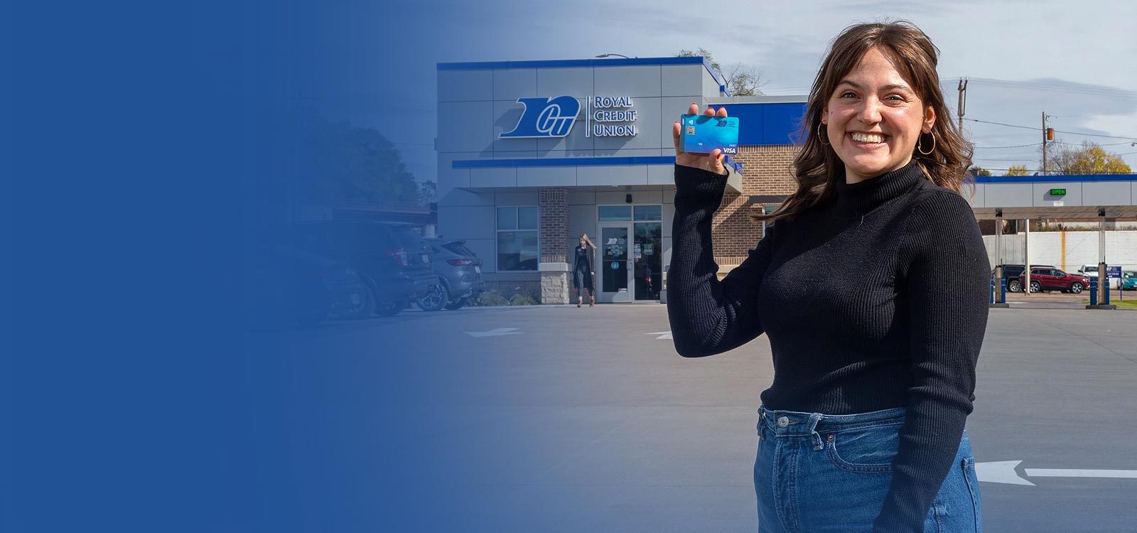 Woman holding an RCU debit card in front of an RCU Office