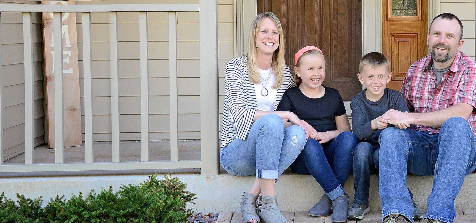 family sitting on porch of house